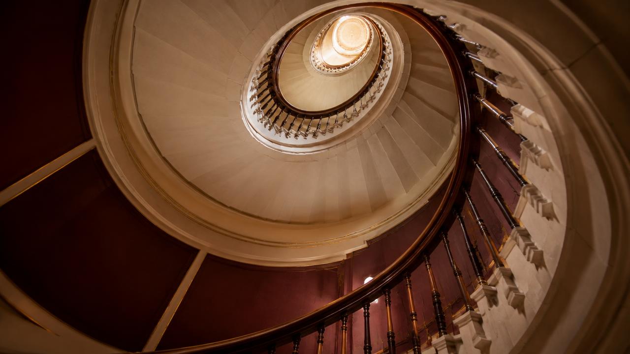 A spiral staircase rising towards warm light